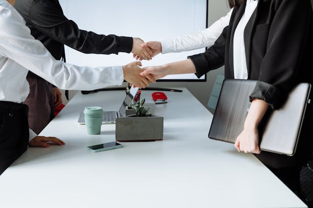 people in a meeting room shaking hands over a long table